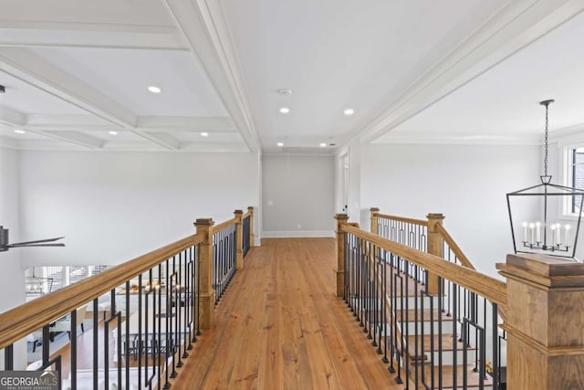 hall with coffered ceiling, beamed ceiling, a notable chandelier, crown molding, and light hardwood / wood-style floors