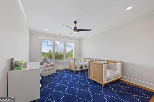 unfurnished bedroom featuring a nursery area, crown molding, and ceiling fan