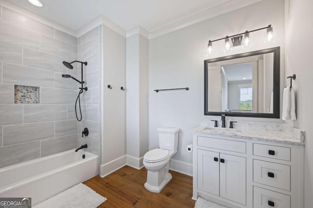 full bathroom with vanity, tiled shower / bath, toilet, ornamental molding, and wood-type flooring