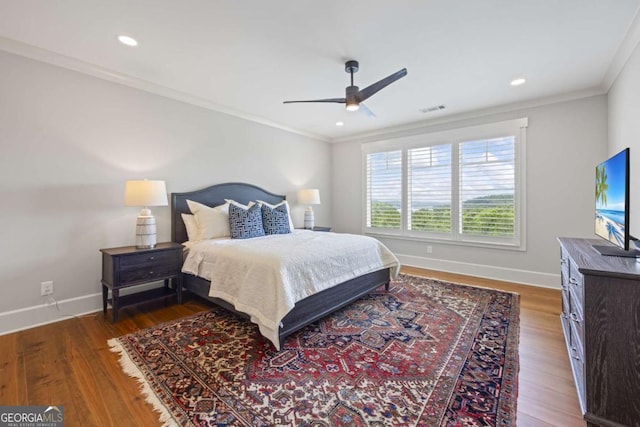 bedroom featuring dark hardwood / wood-style flooring, ceiling fan, and crown molding