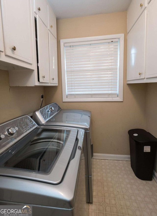 laundry area featuring washing machine and clothes dryer and cabinets