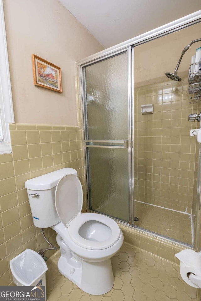 bathroom featuring tile walls, tile patterned flooring, an enclosed shower, and toilet