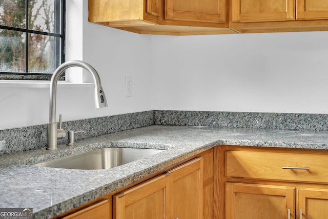 kitchen featuring light stone counters and sink