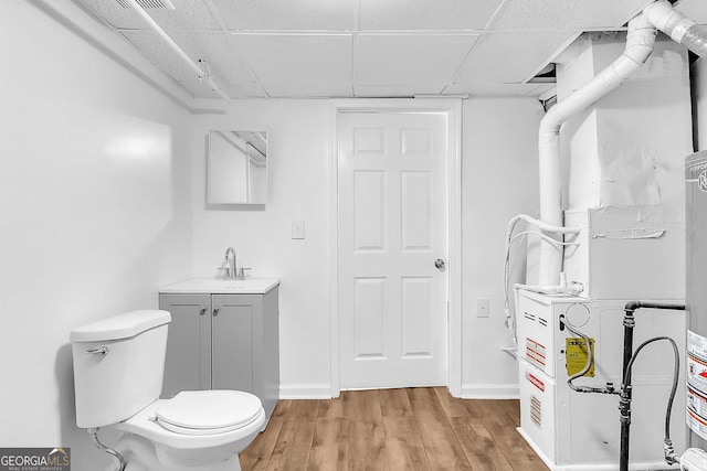 bathroom featuring vanity, wood-type flooring, a paneled ceiling, and toilet