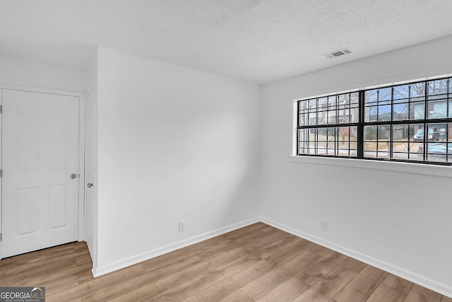 empty room with wood-type flooring and a textured ceiling