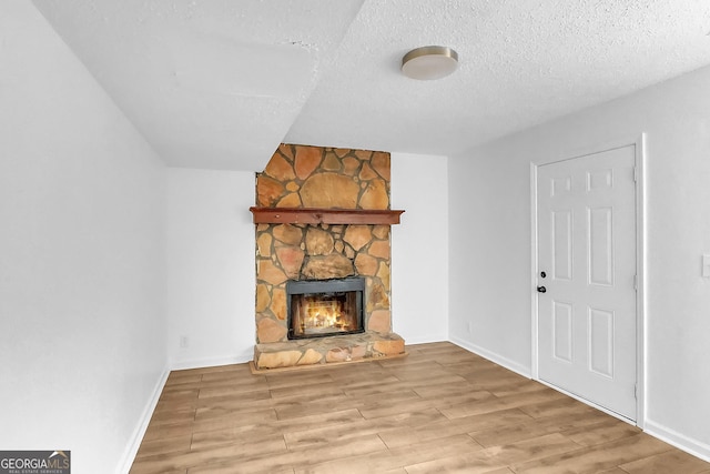 unfurnished living room featuring a fireplace, a textured ceiling, and light hardwood / wood-style flooring