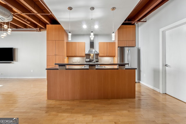 kitchen featuring light hardwood / wood-style flooring, stainless steel refrigerator, hanging light fixtures, and wall chimney exhaust hood