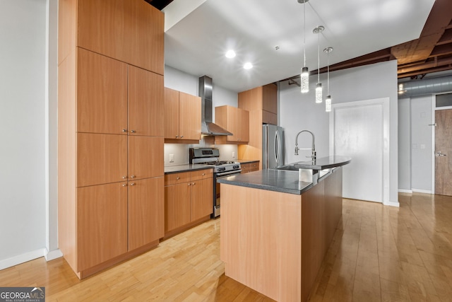 kitchen featuring sink, wall chimney exhaust hood, an island with sink, pendant lighting, and appliances with stainless steel finishes