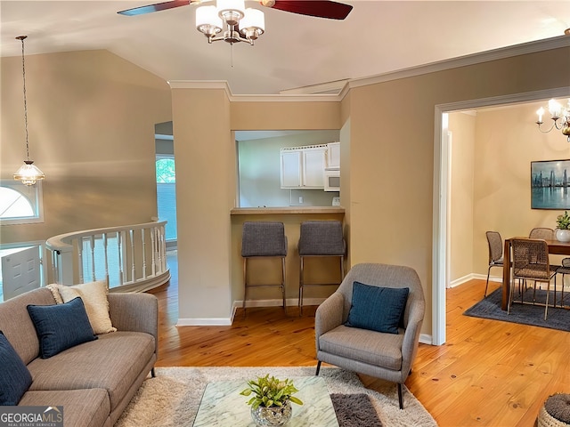 living room featuring ceiling fan with notable chandelier, vaulted ceiling, light hardwood / wood-style flooring, and crown molding