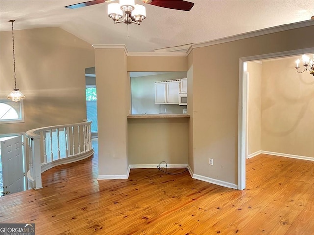 unfurnished living room featuring ceiling fan, light hardwood / wood-style floors, ornamental molding, and vaulted ceiling