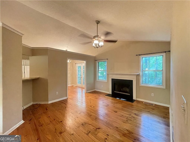 unfurnished living room featuring a textured ceiling, ceiling fan, light hardwood / wood-style flooring, and vaulted ceiling