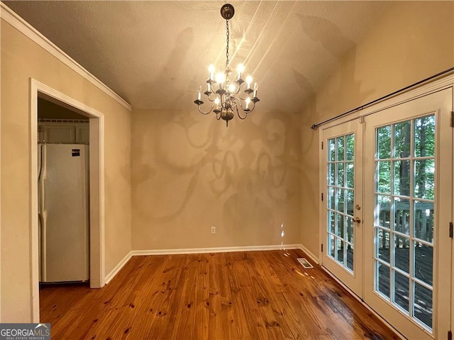 unfurnished dining area featuring a chandelier, french doors, crown molding, and hardwood / wood-style floors