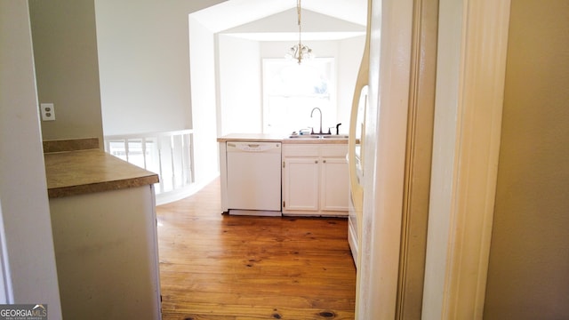 kitchen featuring sink, pendant lighting, light hardwood / wood-style flooring, dishwasher, and white cabinetry