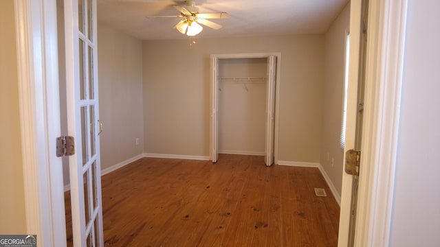 unfurnished bedroom with ceiling fan, a closet, and wood-type flooring