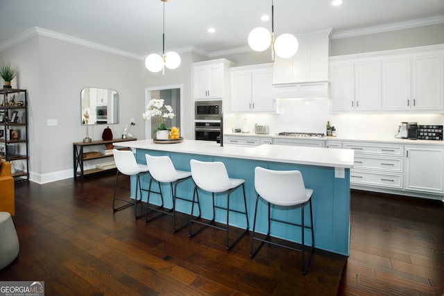 kitchen featuring appliances with stainless steel finishes, tasteful backsplash, a kitchen island with sink, pendant lighting, and white cabinets