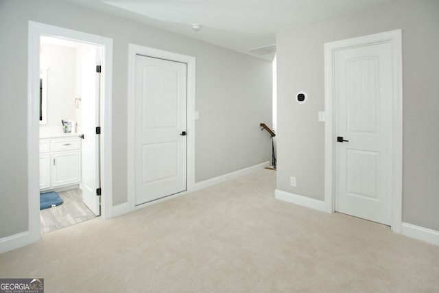 interior space featuring ensuite bathroom and light colored carpet