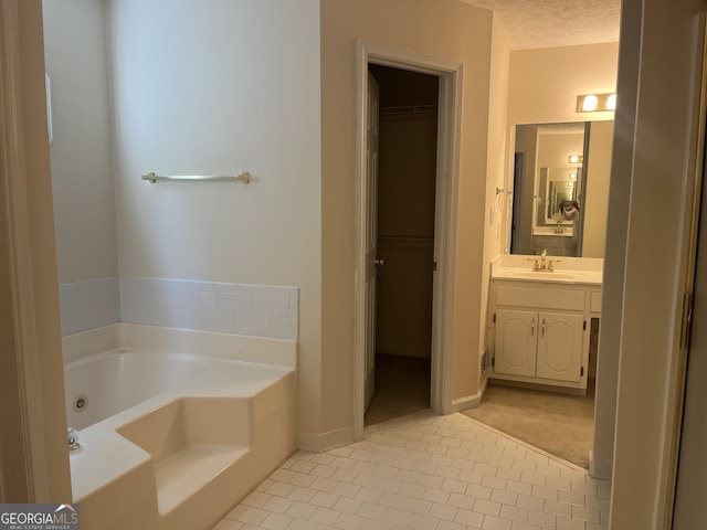 bathroom featuring a bathing tub, vanity, a textured ceiling, and tile patterned floors