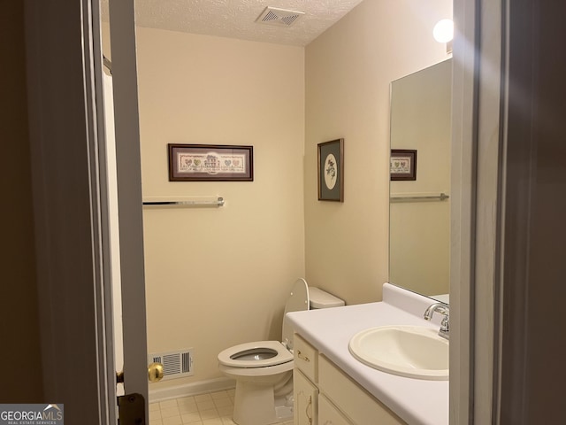 bathroom with vanity, a textured ceiling, and toilet