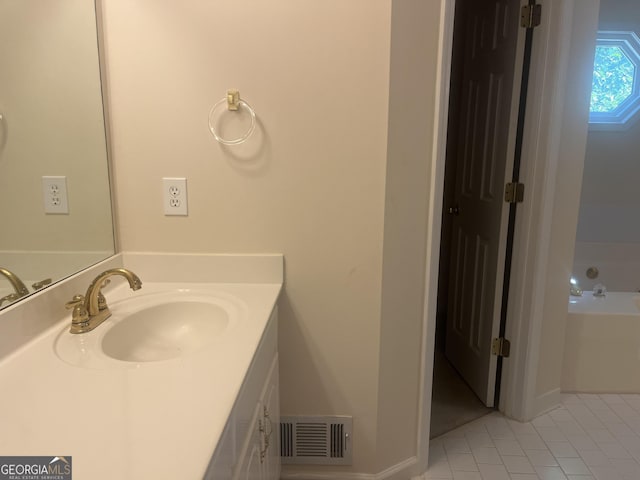 bathroom featuring tile patterned flooring, vanity, and a tub to relax in