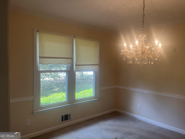 spare room featuring carpet floors and a chandelier