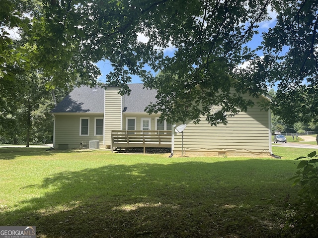 rear view of house featuring central air condition unit, a wooden deck, and a lawn