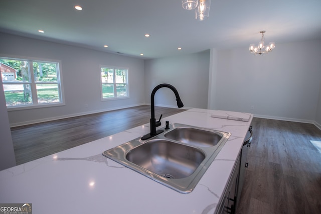 kitchen with light stone counters, sink, decorative light fixtures, and a notable chandelier