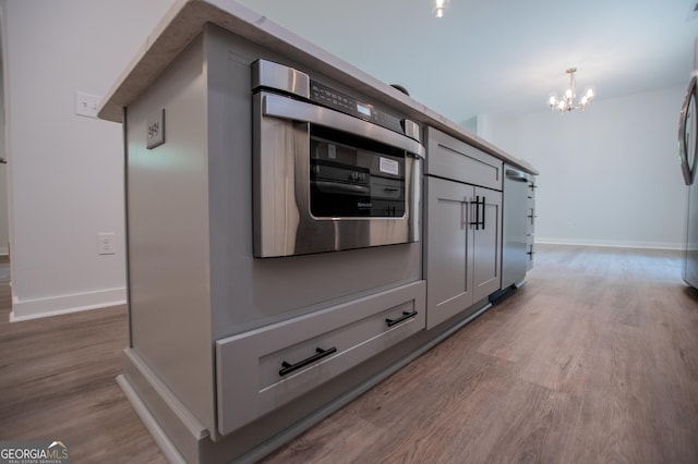 kitchen with hardwood / wood-style flooring, oven, pendant lighting, and a chandelier