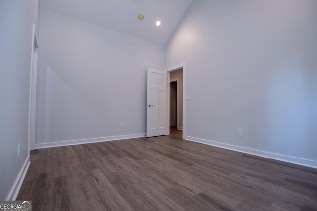 empty room featuring dark wood-type flooring and high vaulted ceiling