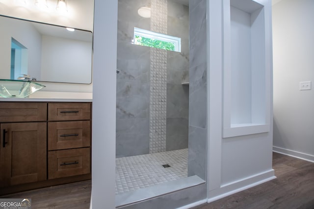 bathroom featuring hardwood / wood-style flooring, vanity, and a tile shower