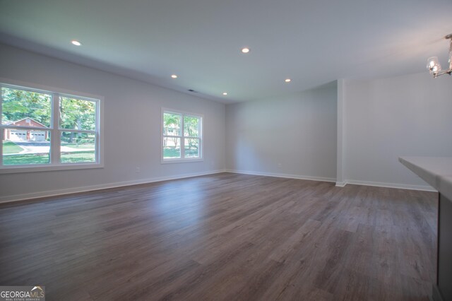 spare room with a notable chandelier and dark wood-type flooring