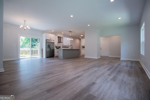 unfurnished living room with sink, light hardwood / wood-style floors, and a notable chandelier