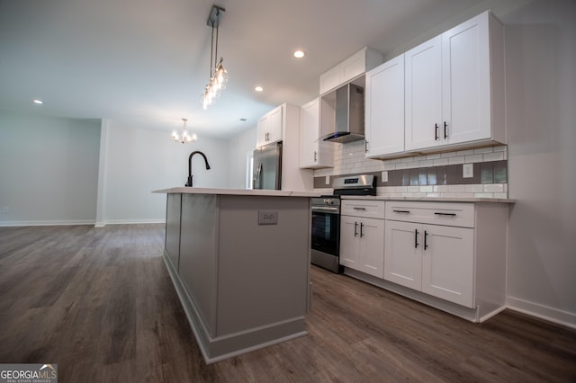 kitchen featuring a center island with sink, wall chimney exhaust hood, white cabinetry, and appliances with stainless steel finishes