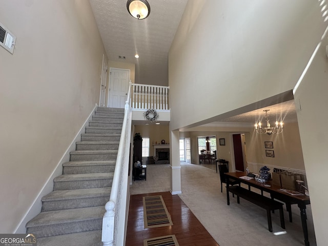 staircase featuring a chandelier, a textured ceiling, a fireplace, wood finished floors, and baseboards