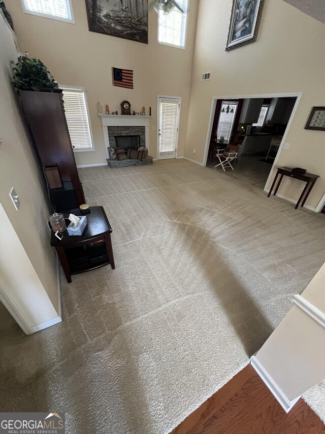 living room with ceiling fan, carpet floors, and a high ceiling