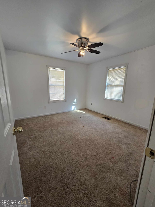 carpeted spare room with ceiling fan and plenty of natural light