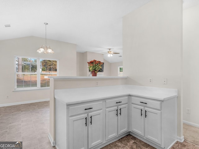 kitchen with kitchen peninsula, ceiling fan with notable chandelier, and vaulted ceiling