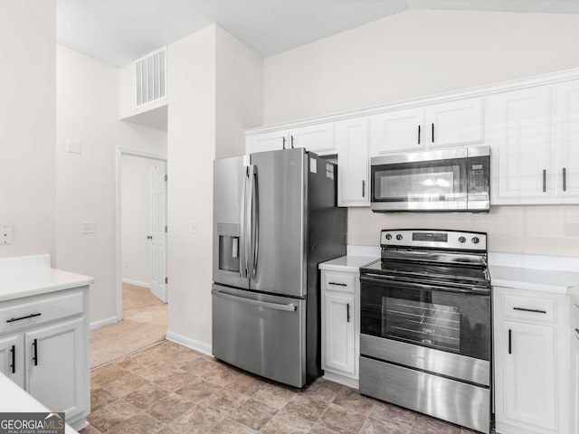 kitchen with white cabinets, stainless steel appliances, and lofted ceiling