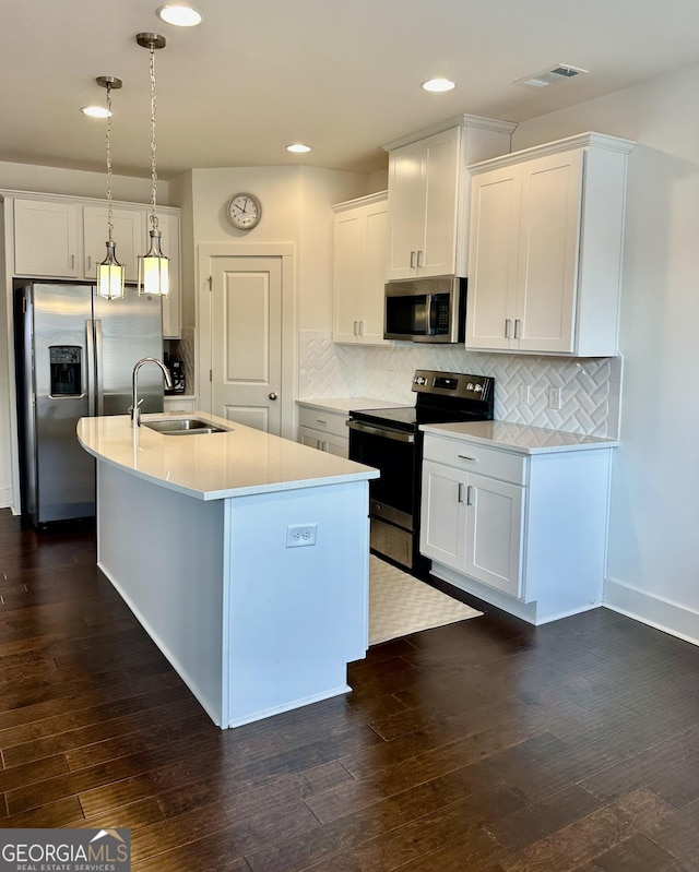 kitchen with a kitchen island with sink, sink, decorative light fixtures, white cabinetry, and stainless steel appliances