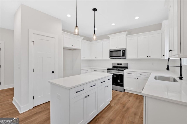 kitchen featuring sink, a center island, appliances with stainless steel finishes, white cabinets, and light wood-type flooring