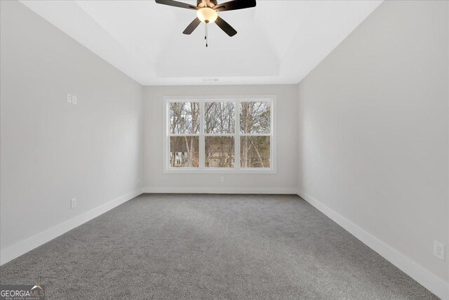 carpeted empty room featuring ceiling fan and a tray ceiling