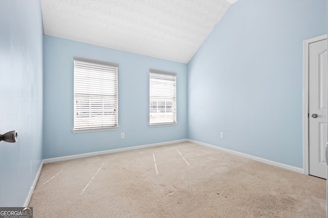 carpeted spare room with a textured ceiling and lofted ceiling