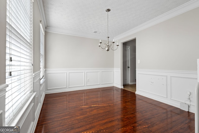 unfurnished dining area with ornamental molding, a textured ceiling, dark hardwood / wood-style flooring, and a notable chandelier