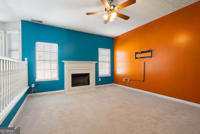 unfurnished living room with ceiling fan, light carpet, and a textured ceiling