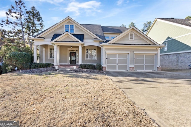 view of front of property featuring covered porch, a garage, and a front yard