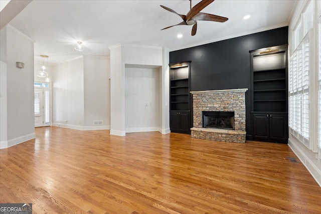 unfurnished living room with a fireplace, light hardwood / wood-style floors, built in features, and a wealth of natural light