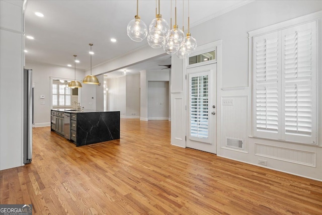 kitchen with pendant lighting, sink, stainless steel refrigerator, and an island with sink