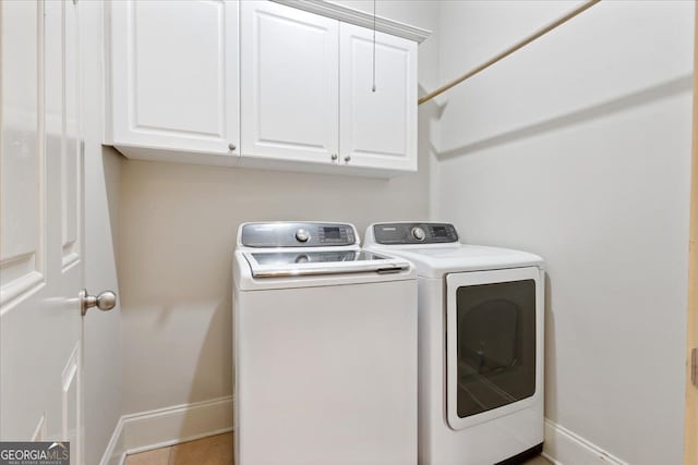 clothes washing area with cabinets, tile patterned flooring, and washer and clothes dryer