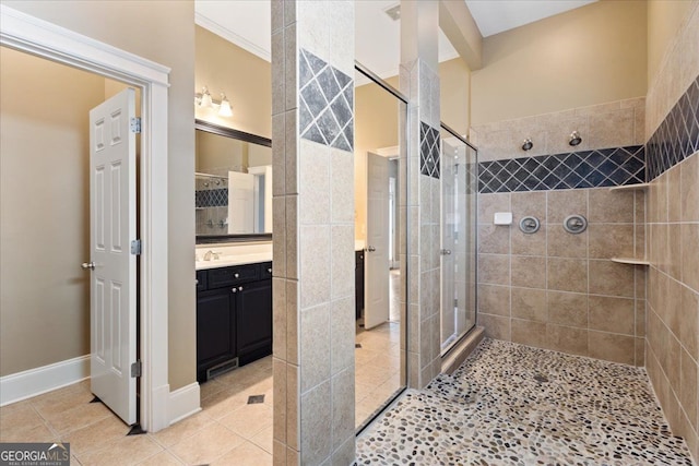 bathroom with tile patterned flooring, vanity, ornamental molding, and tiled shower