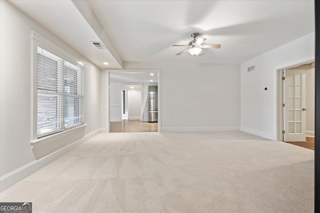 carpeted spare room featuring ceiling fan and plenty of natural light