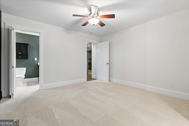 unfurnished bedroom featuring ceiling fan, light carpet, and connected bathroom